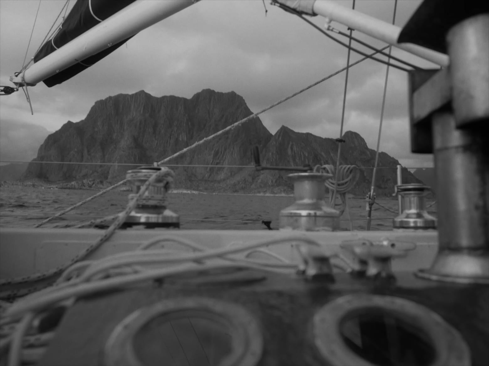 B&W sailboat offshore from mountain landscape