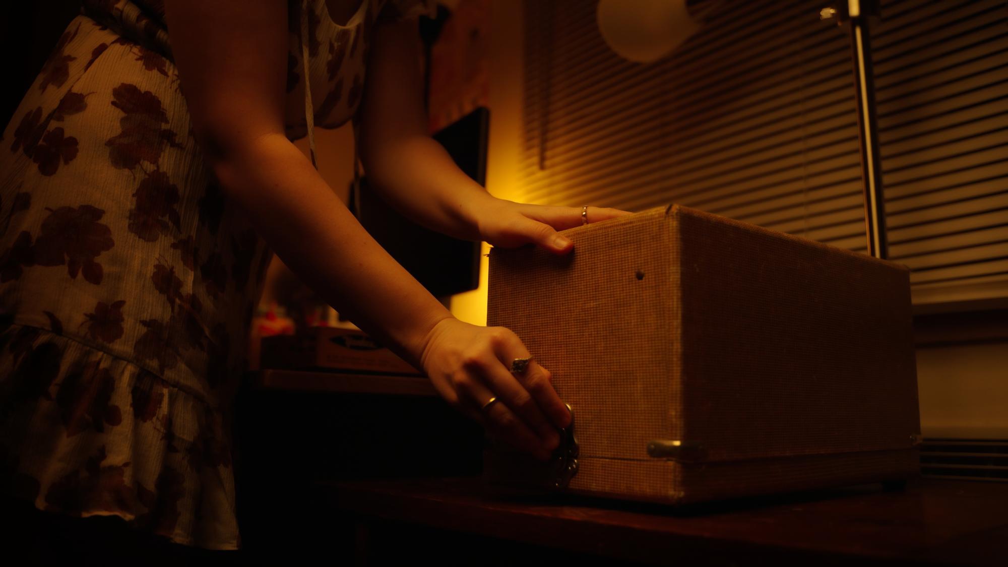 Hands reaching to unlatch vintage slide projector case