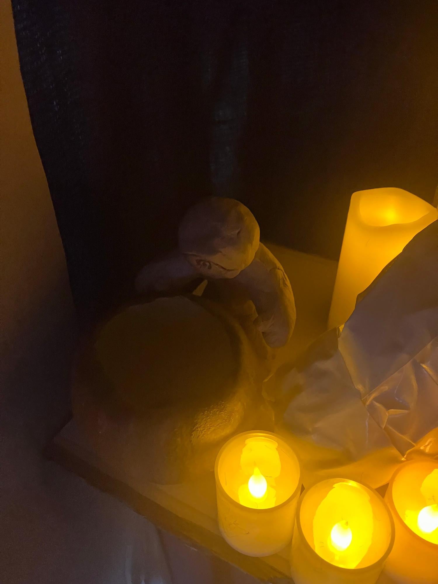 Clay figure surrounded by candles