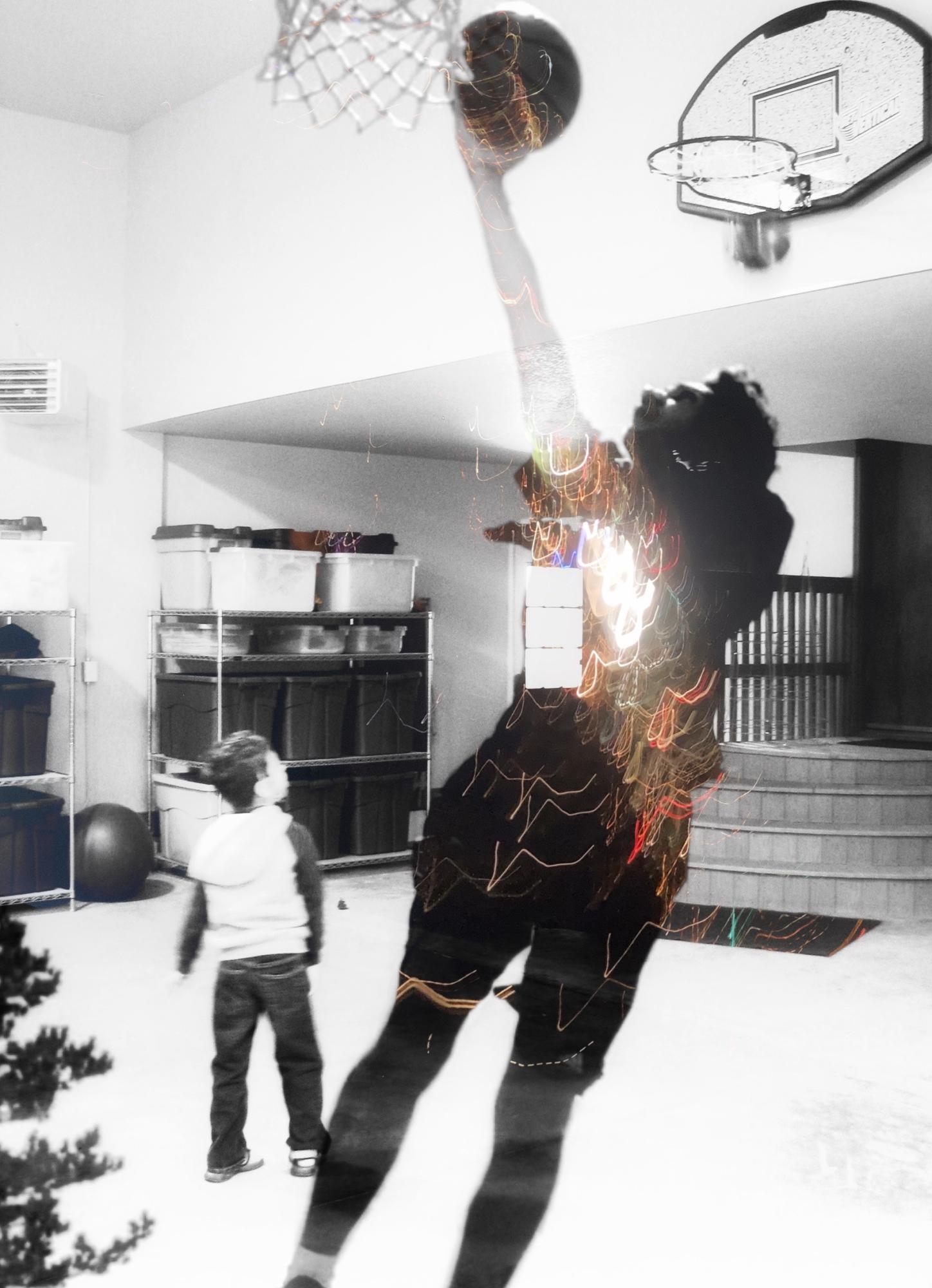black and white image of a man playing basketball with a child