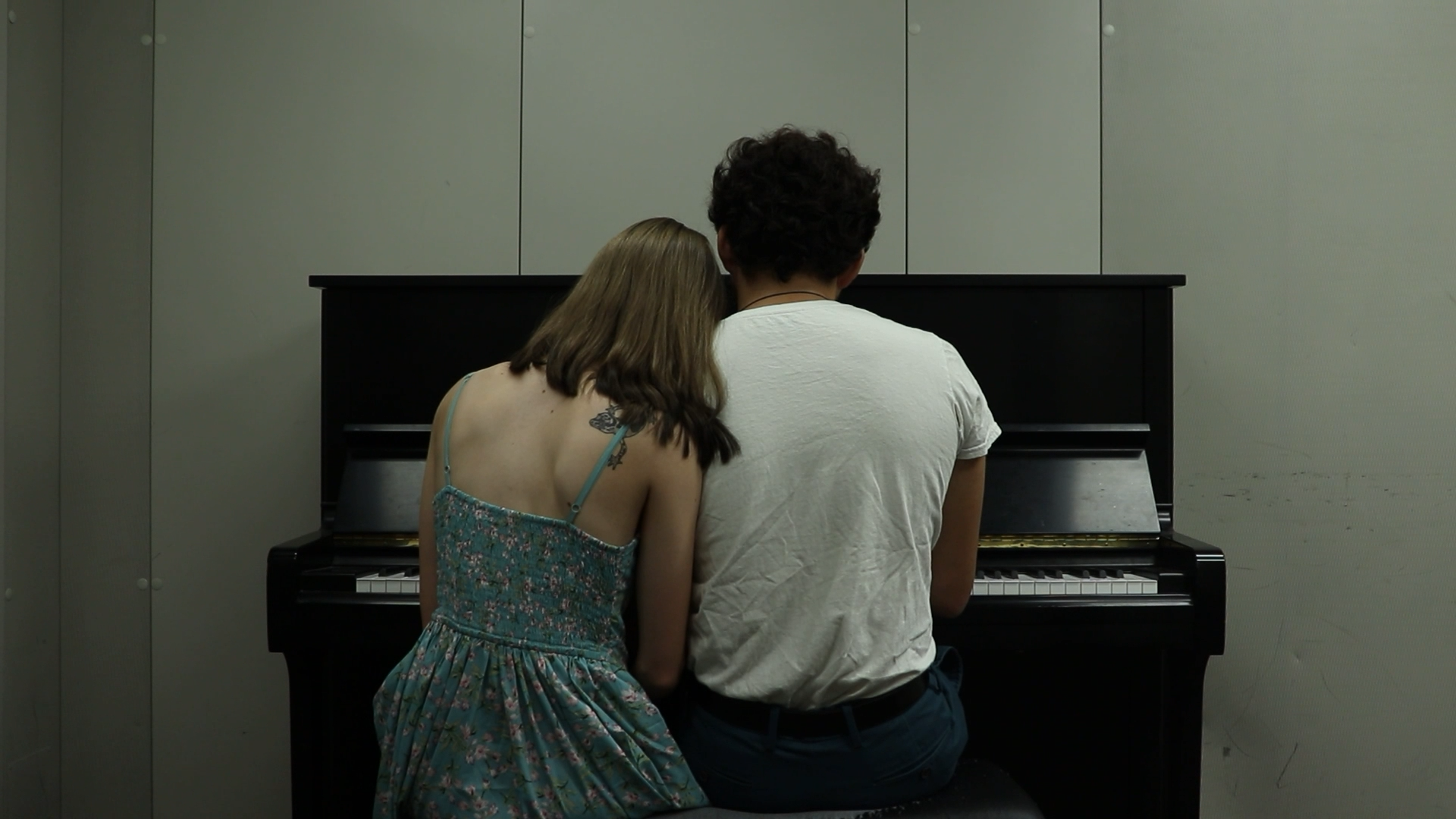 a man and woman sitting on the same piano bench