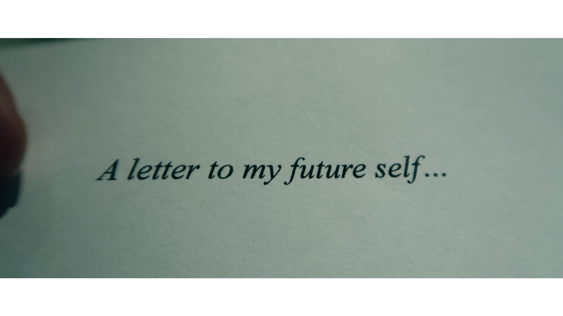 Image of a paper that says “A letter to my future self…” Part of a finger can be seen clutching the paper toward the edge of the image frame