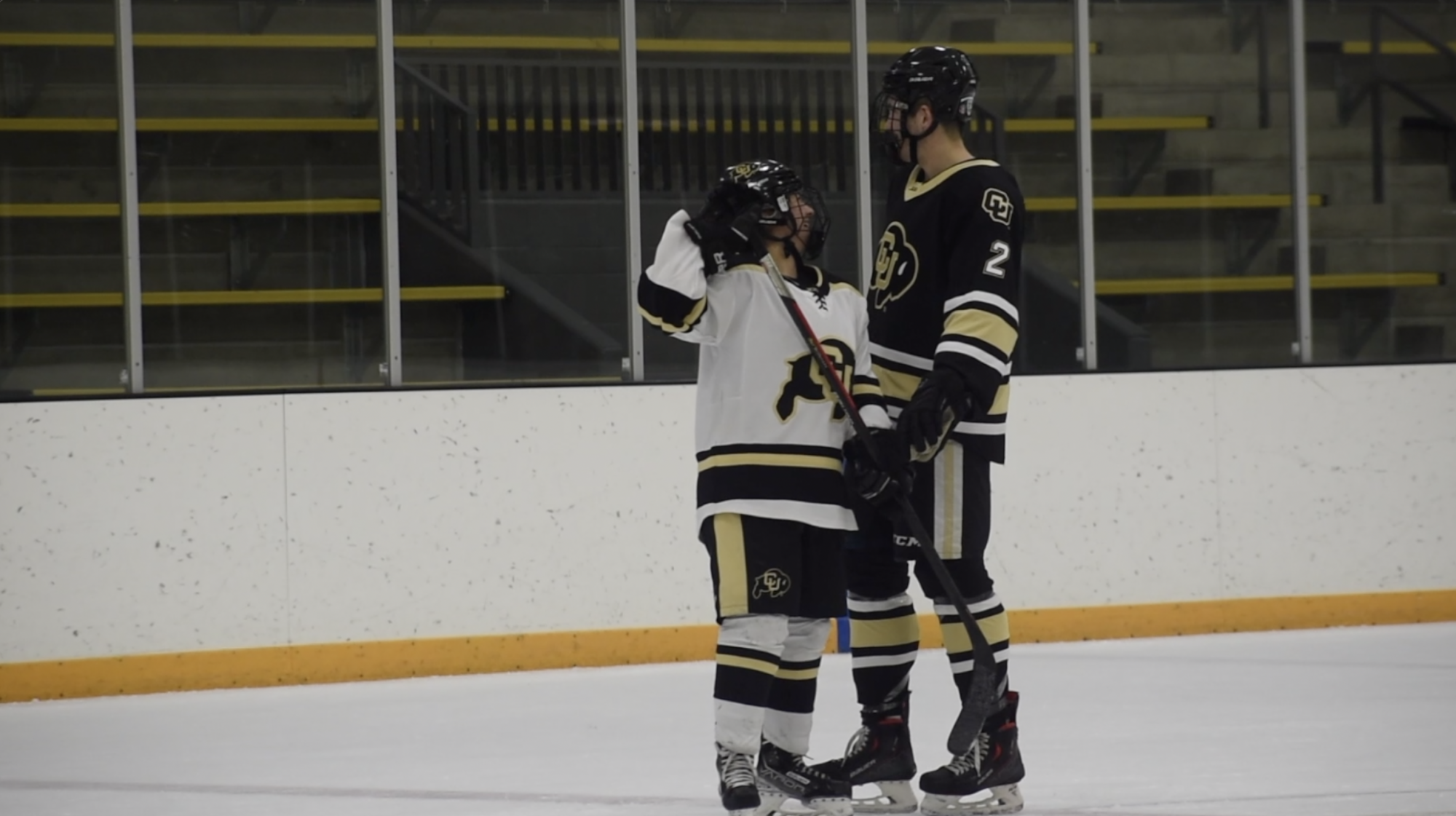 A girl hockey player and a boy hockey player standing next to each other mid-scrimmage