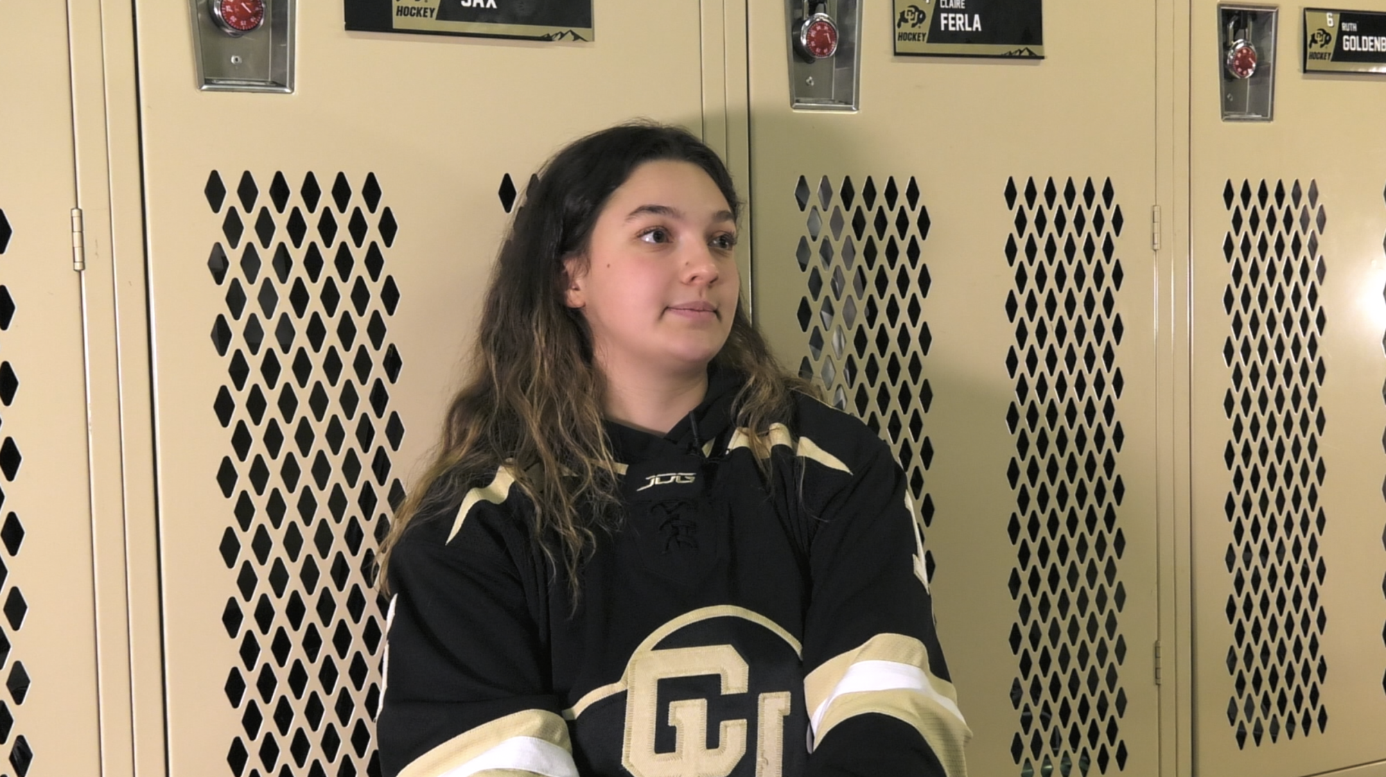 Interviewee "Zaya Sax" mid-interview sitting in front of lockers in locker room