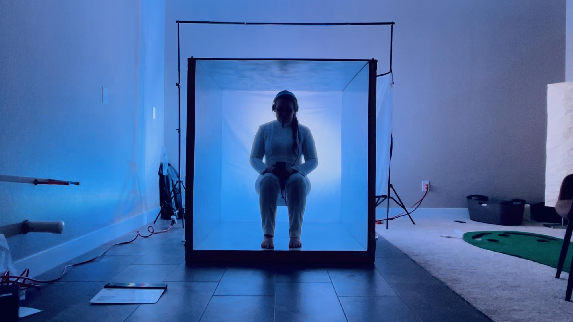 a person sitting in a box with dramatic blue lighting