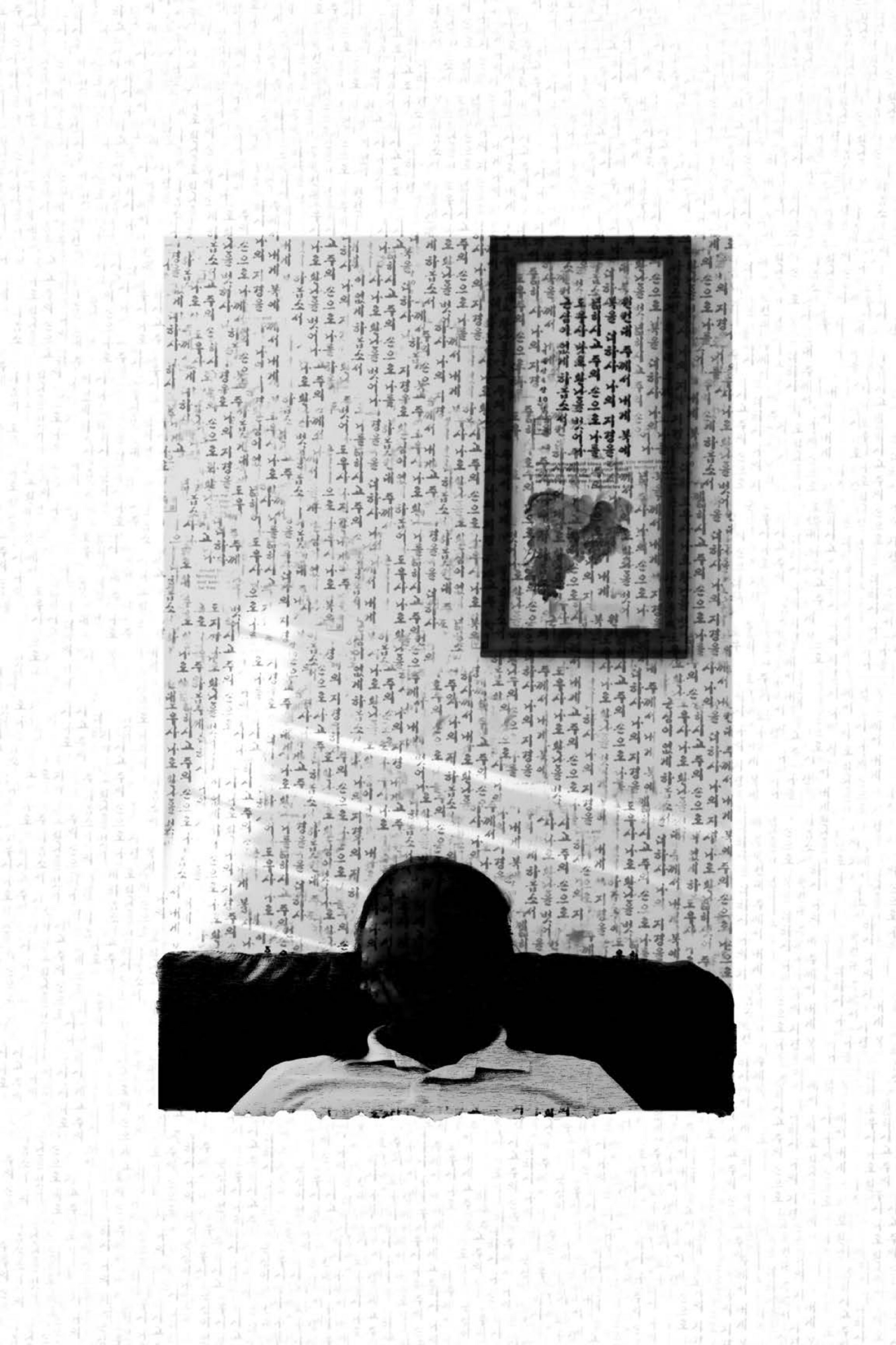a black and white photo of Korean scripture written all over the wall with a faceless figure sitting in the center