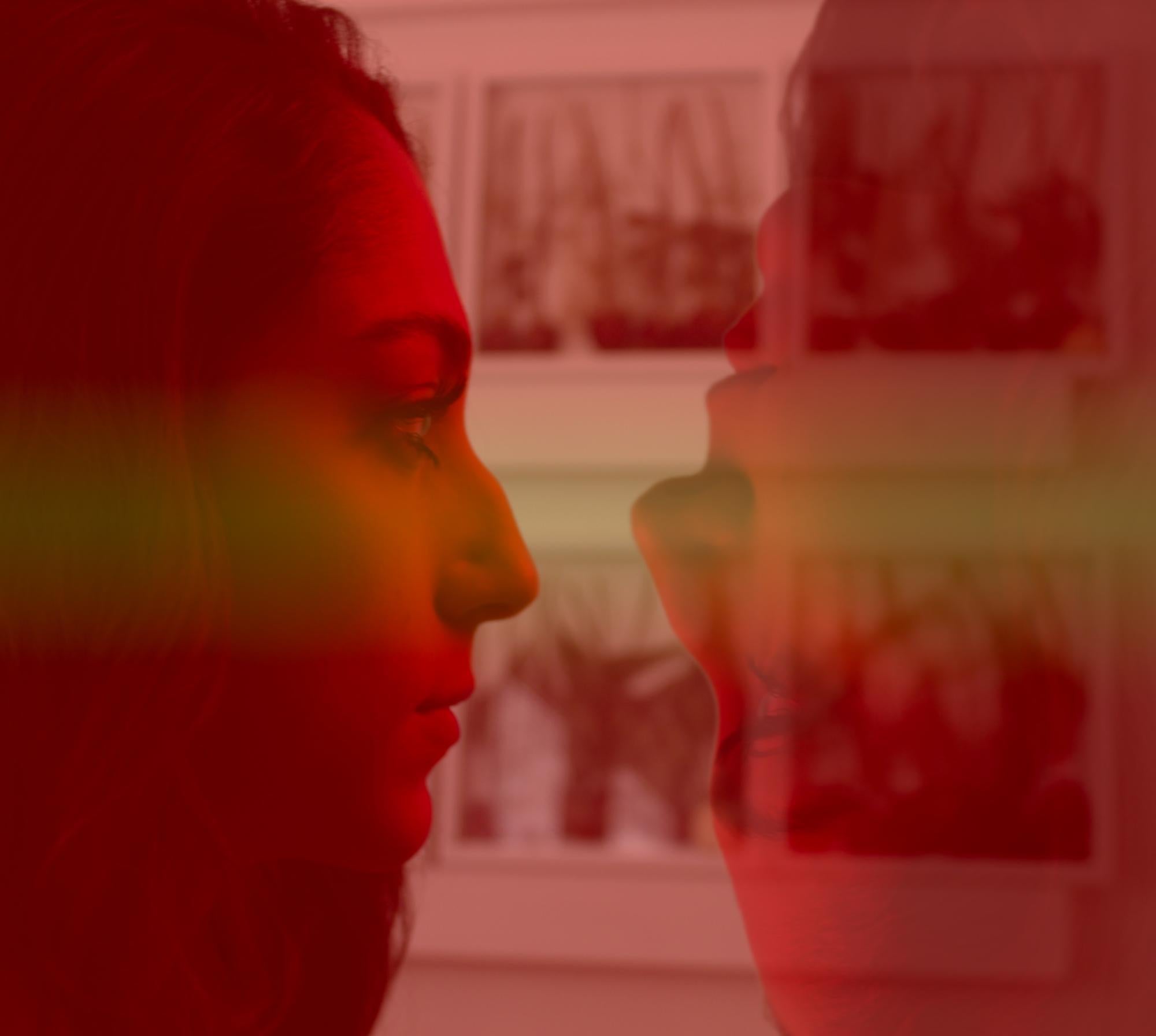- Two images of the same girl face each other in front of a wall with clear photo boxes full of dead flowers