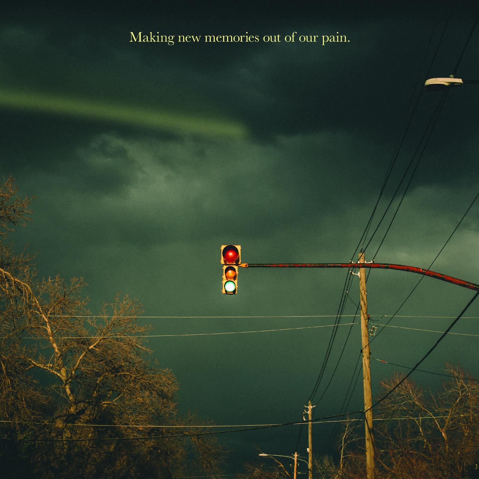 An image of a traffic light glowing green on a cloudy, moody-looking day. Complimented with power wires and grainy textures. In a serif typeface colored pale yellow, "Making new memories out of our pain." This is a standout lyric from "Context Clues".