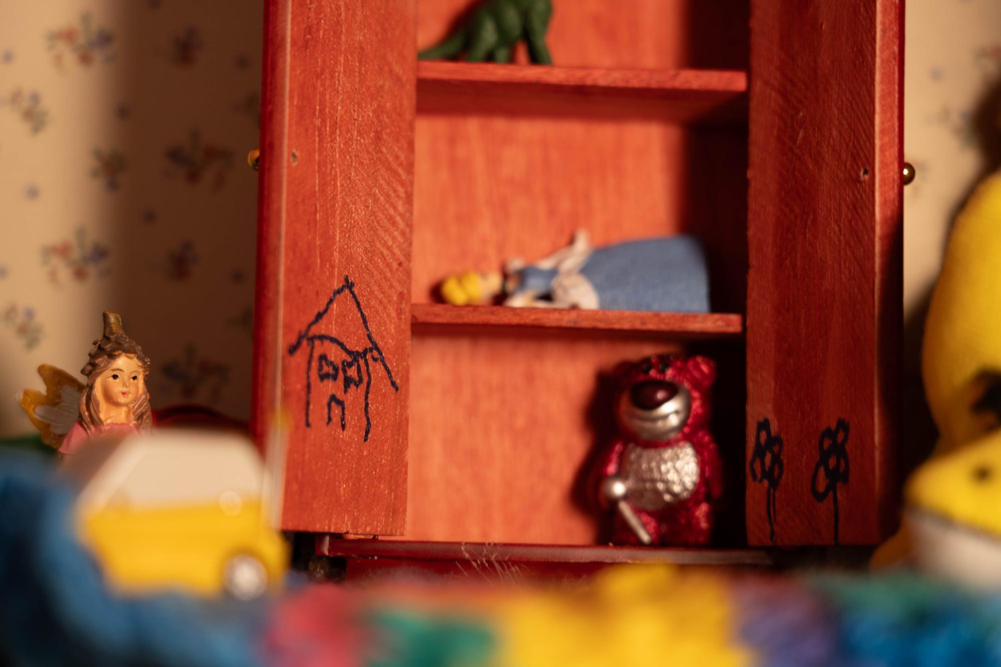 A close up shot inside of a child's playroom full of toys focusing on two drawings itched into a dresser