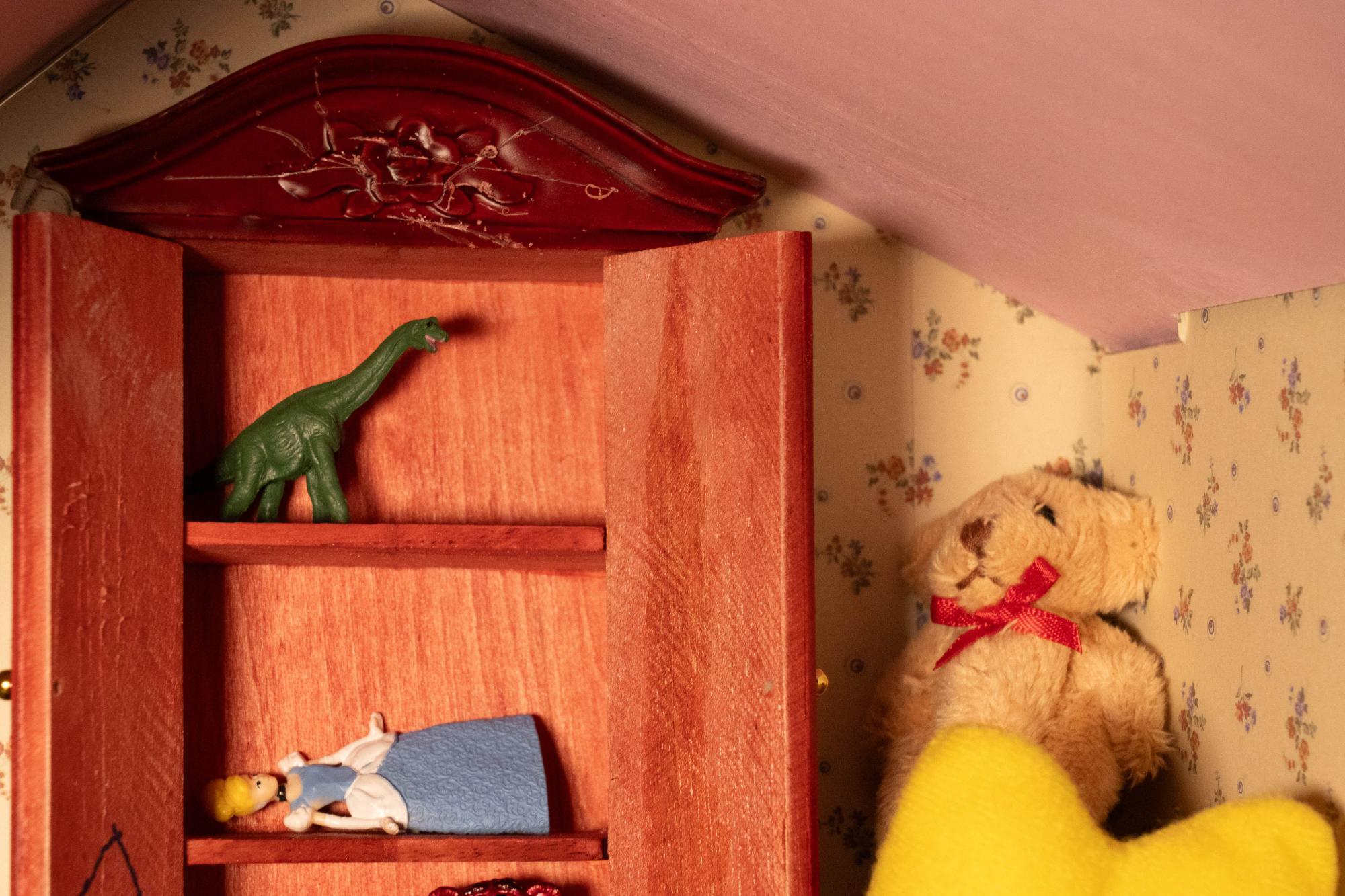 shot of the low angled ceiling of the playroom, focusing on a teddy bear in the corner and the scratches covering the top of the dresser