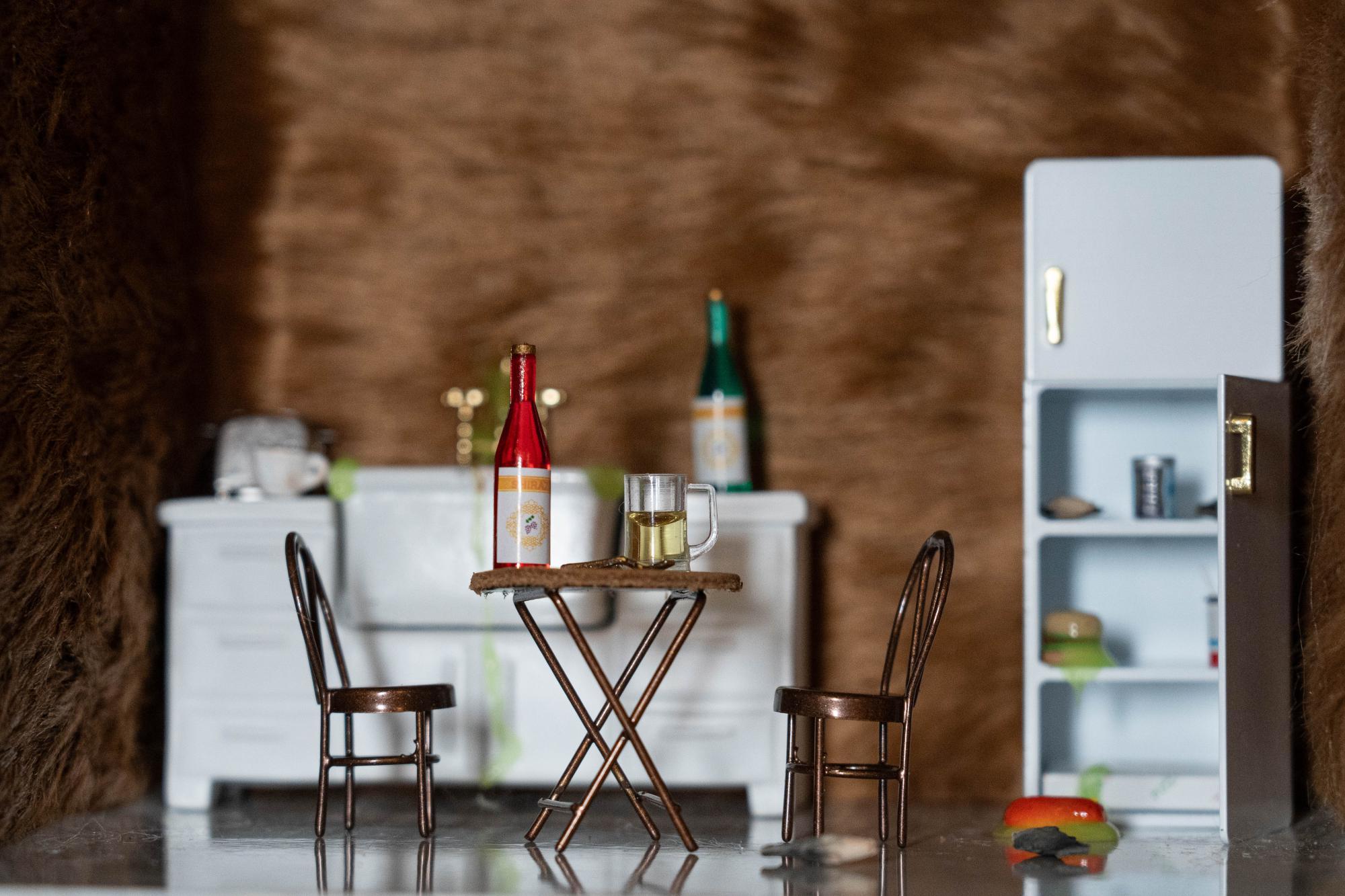 Kitchen set with fur covering the walls, focusing on the leather table set with alcohol on the table and rotting food in the fridge and on the floor