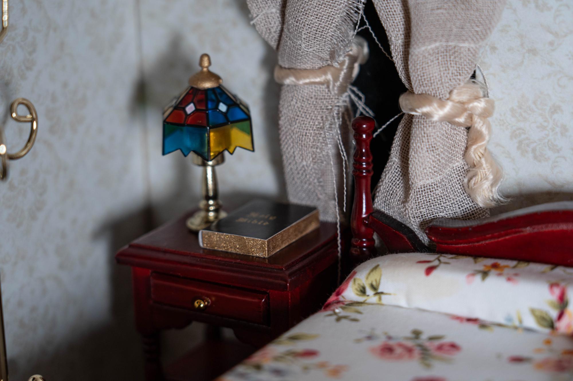 Close up shot of motel room bedside table with a bible and colorful lamp resting on it
