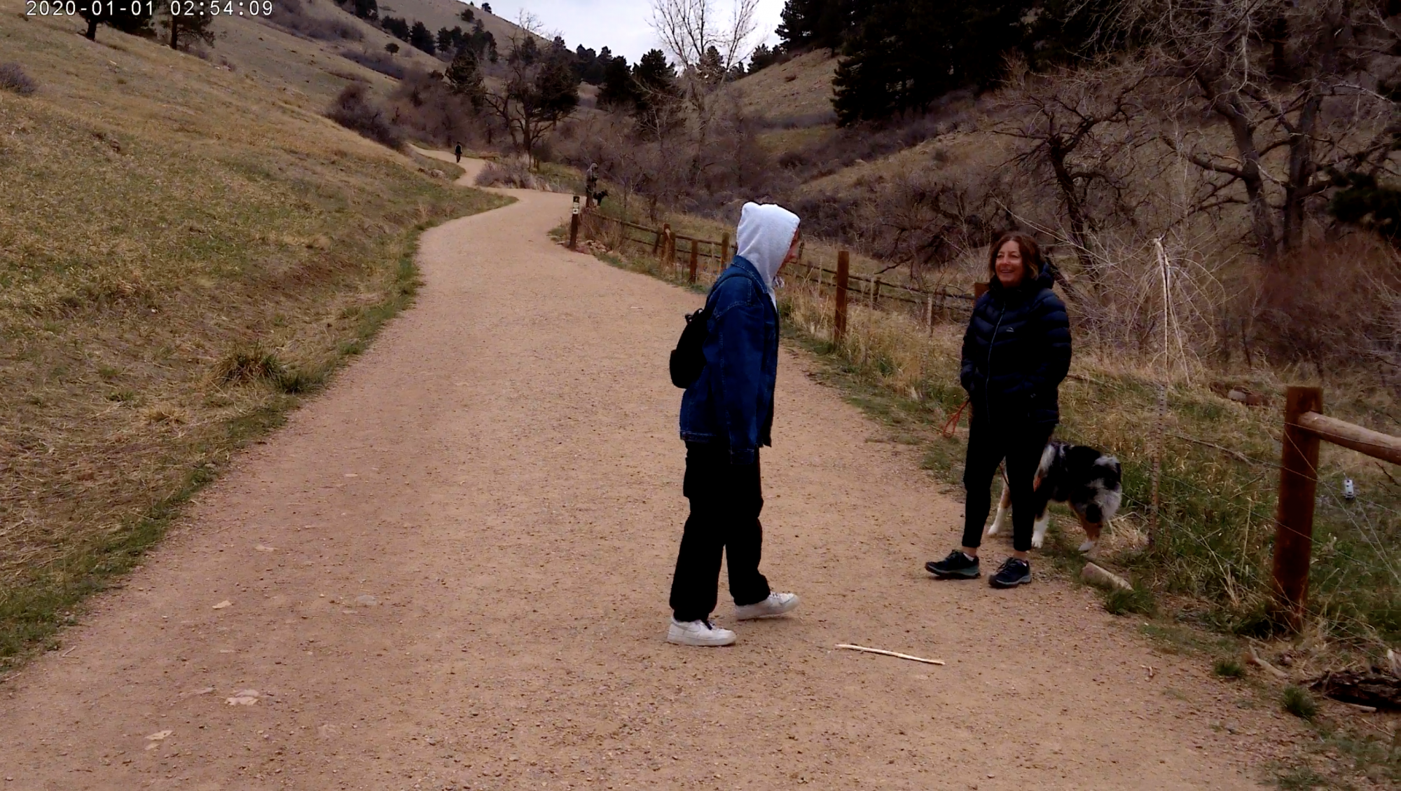 Two people and a dog on a hiking trail