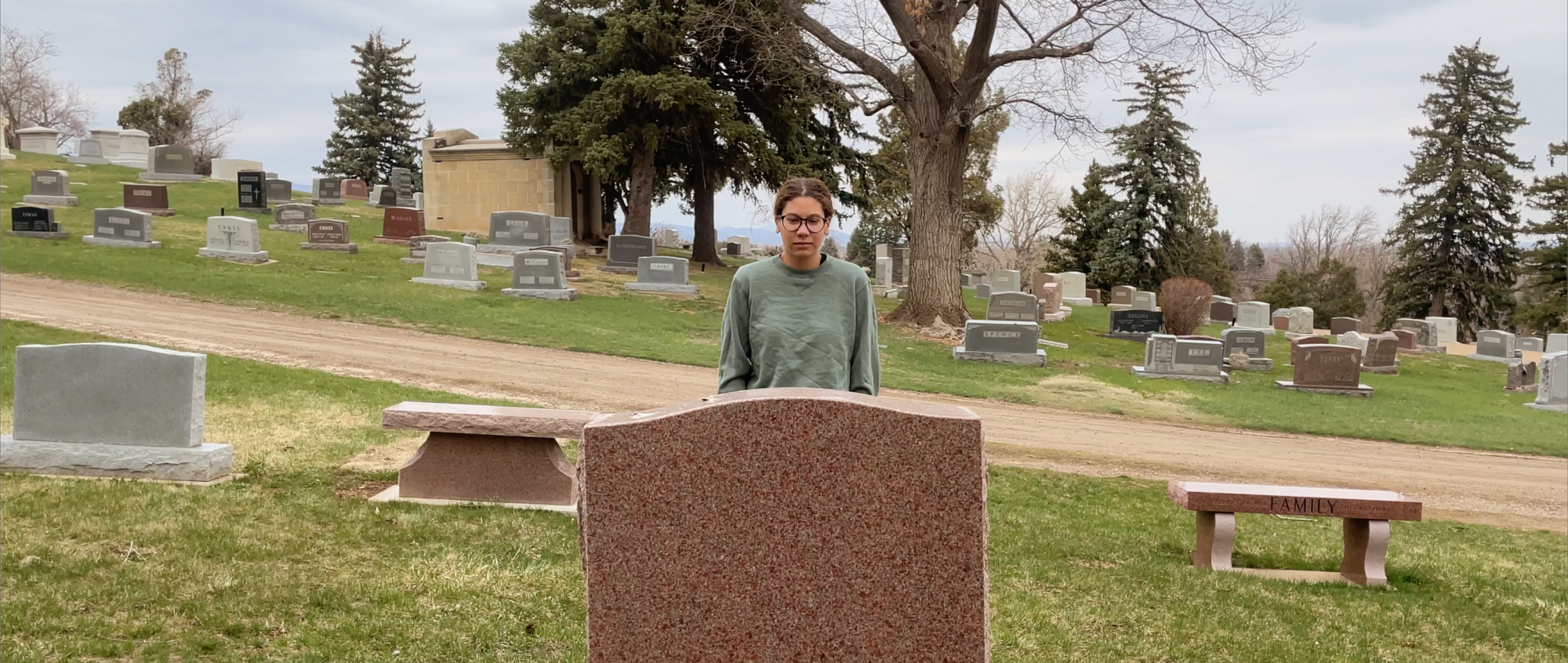 Person looking at a tombstone in a cemetery