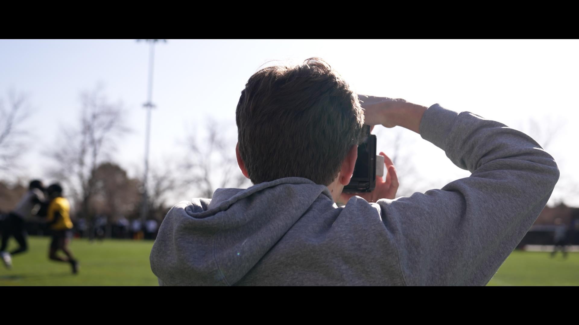 Eli Milner (subject) shooting photos at football practice