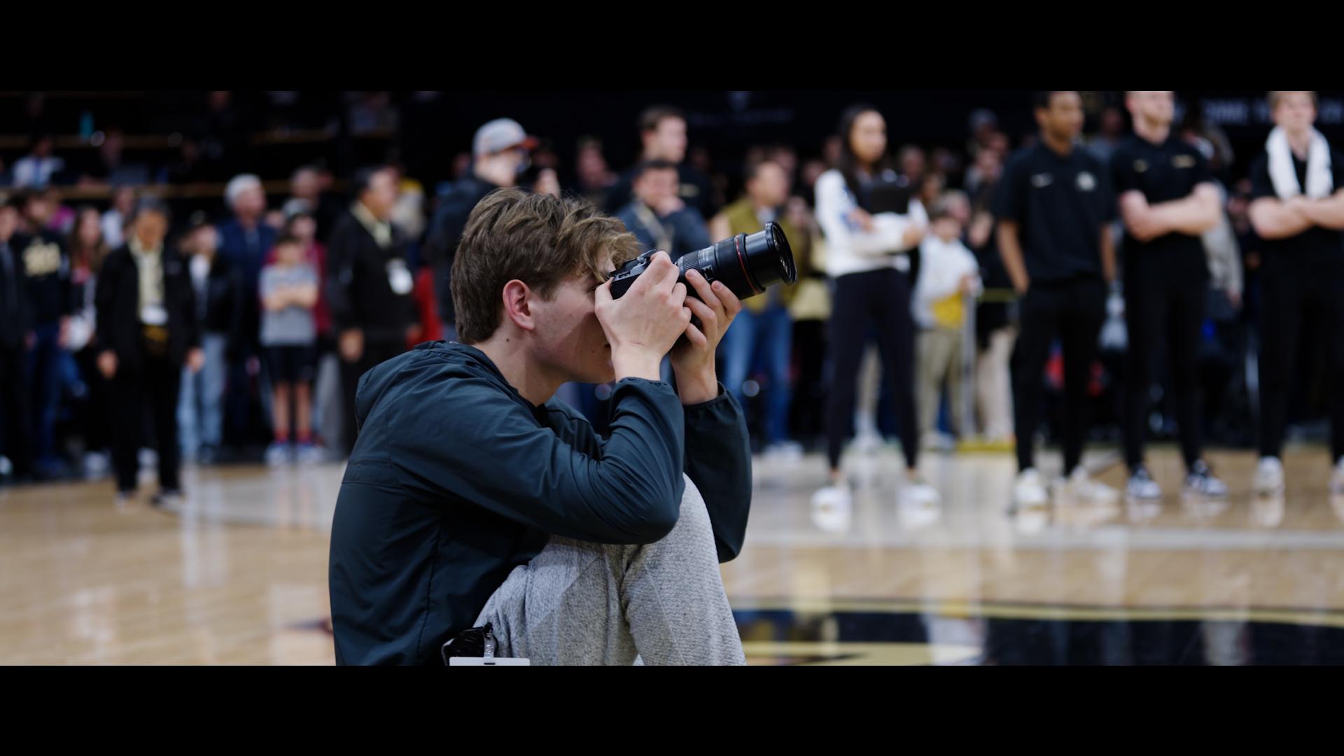 Eli Milner (subject) shooting photos at basketball game