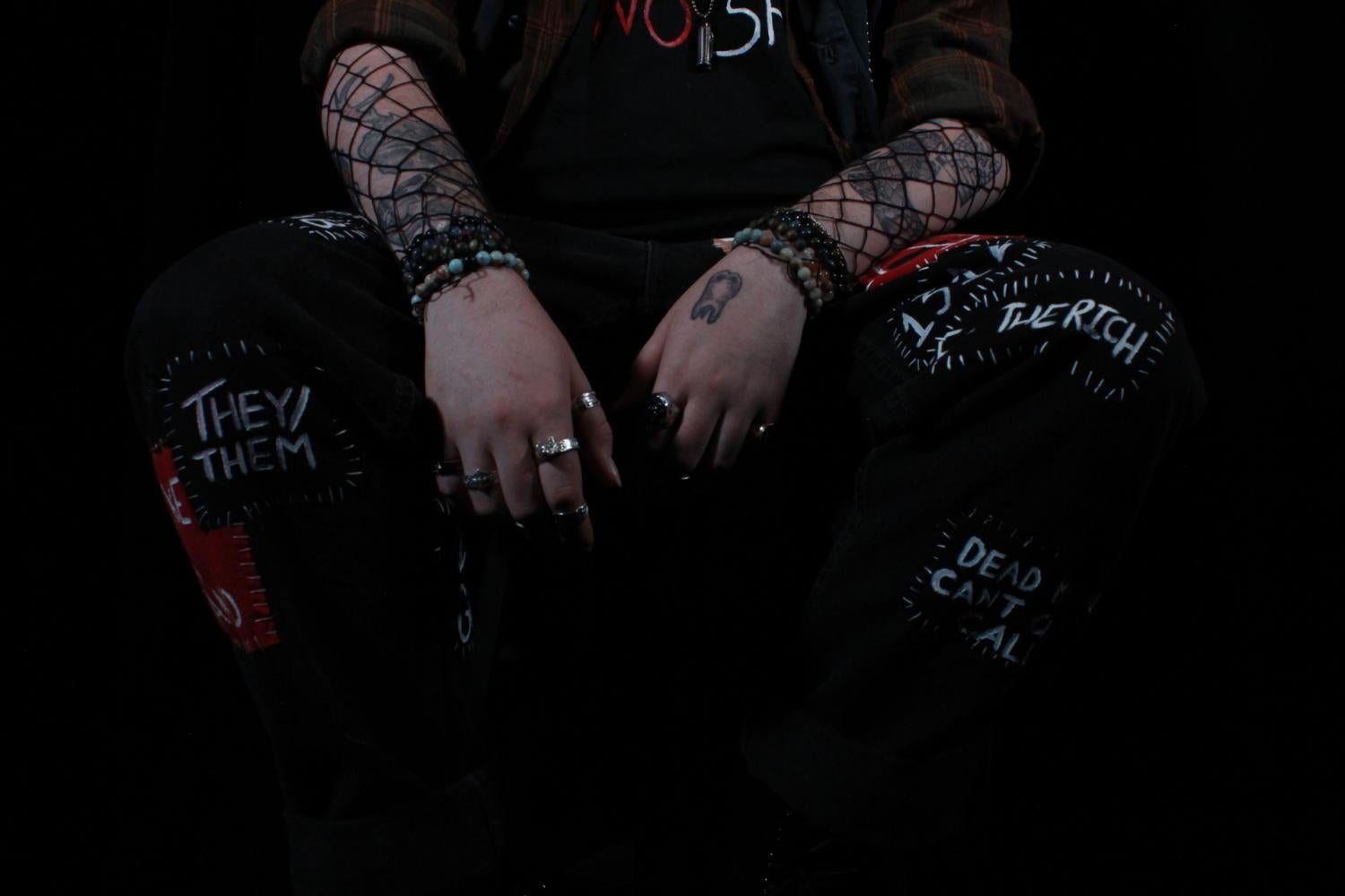 torso and legs, arms resting on knees, hands loose in front, patches covering jeans, chest down