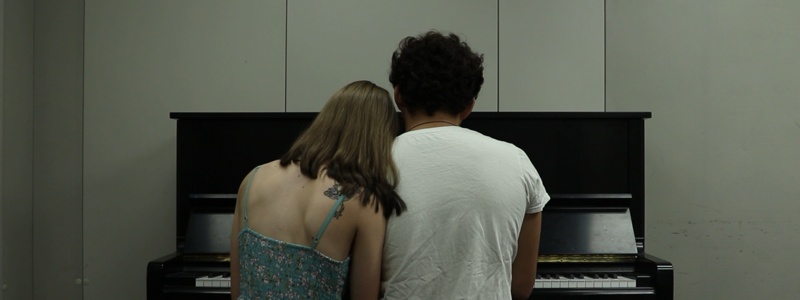 man and woman sitting together on a piano bench