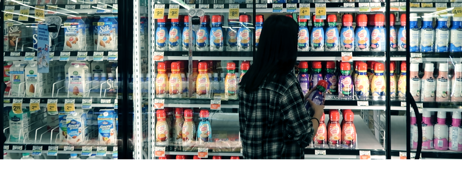 Woman walking by fridge with coffee creamer