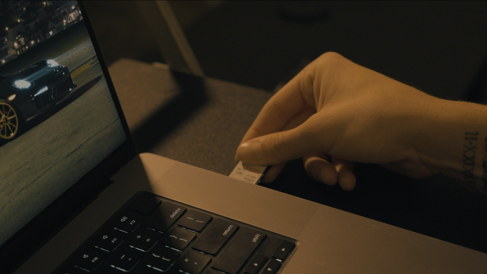 Angus inserting an SD card from his camera into his laptop in his living room at night