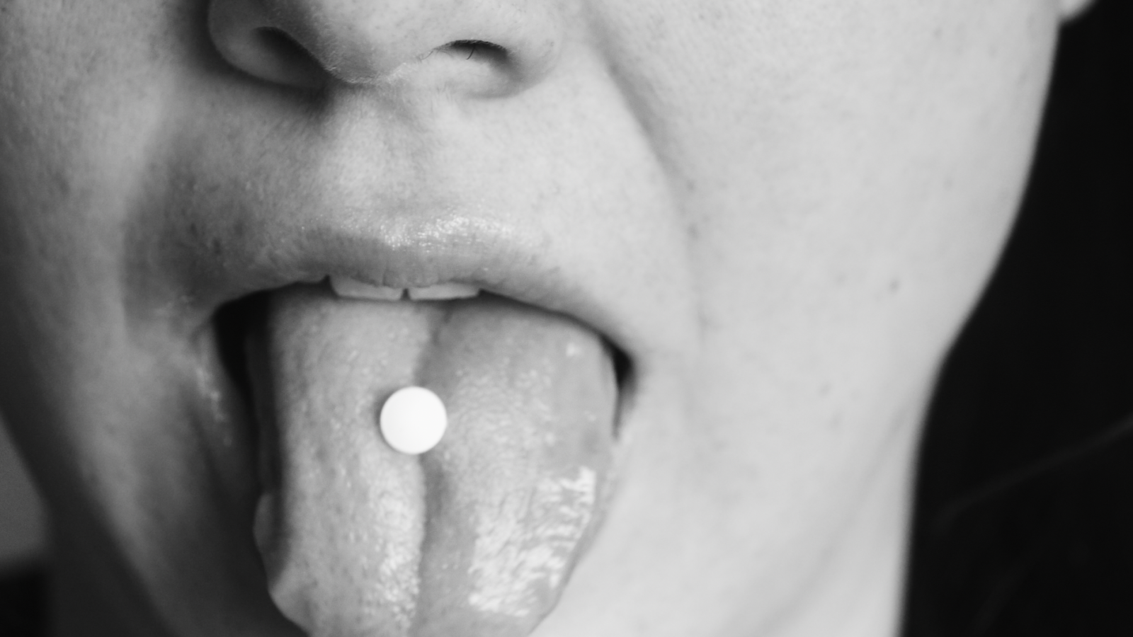 close up of a tongue with a pill on it