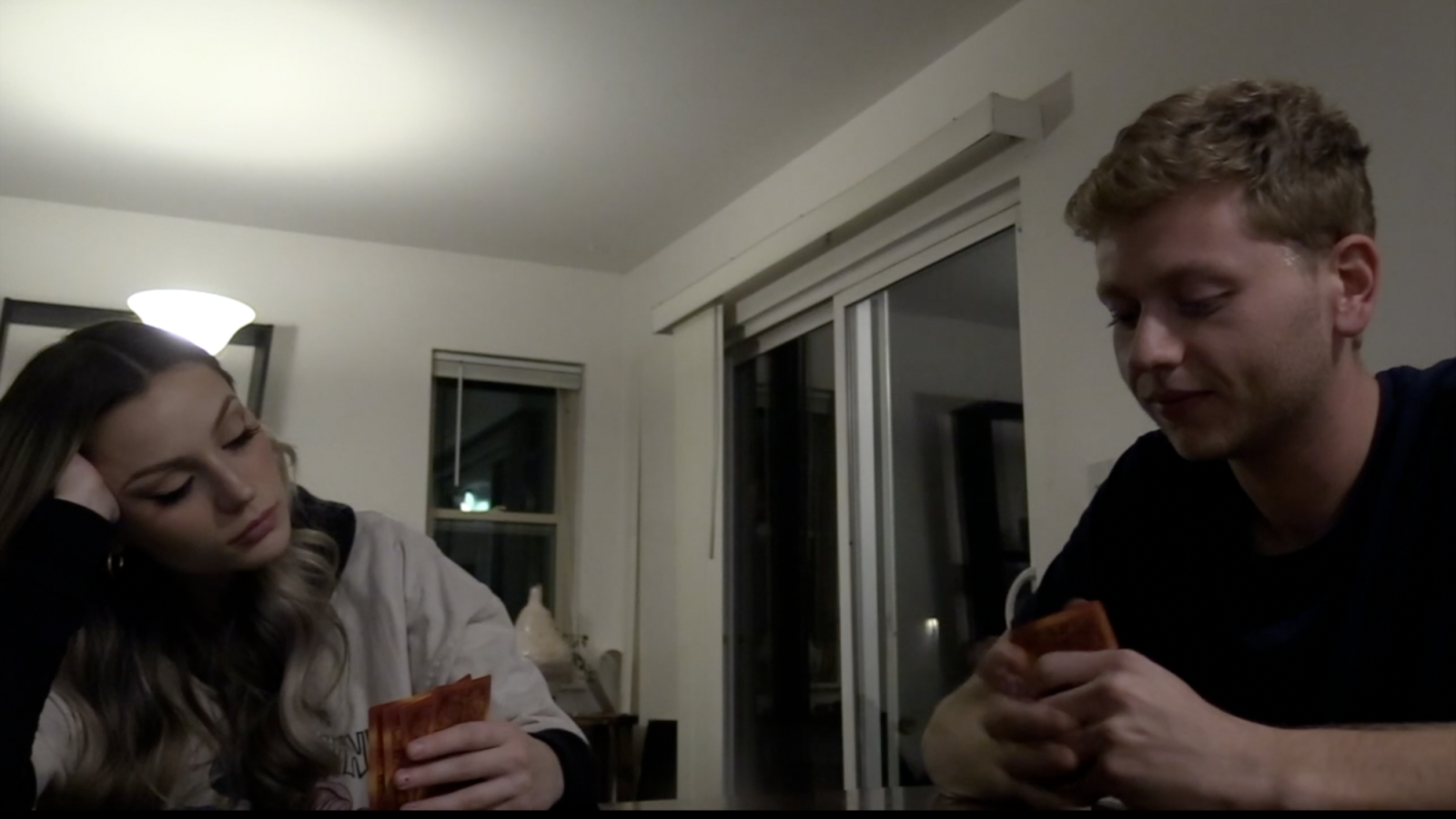The girl playing her final game of cards with her roommates. She's clearly tired and not paying attention to her game.