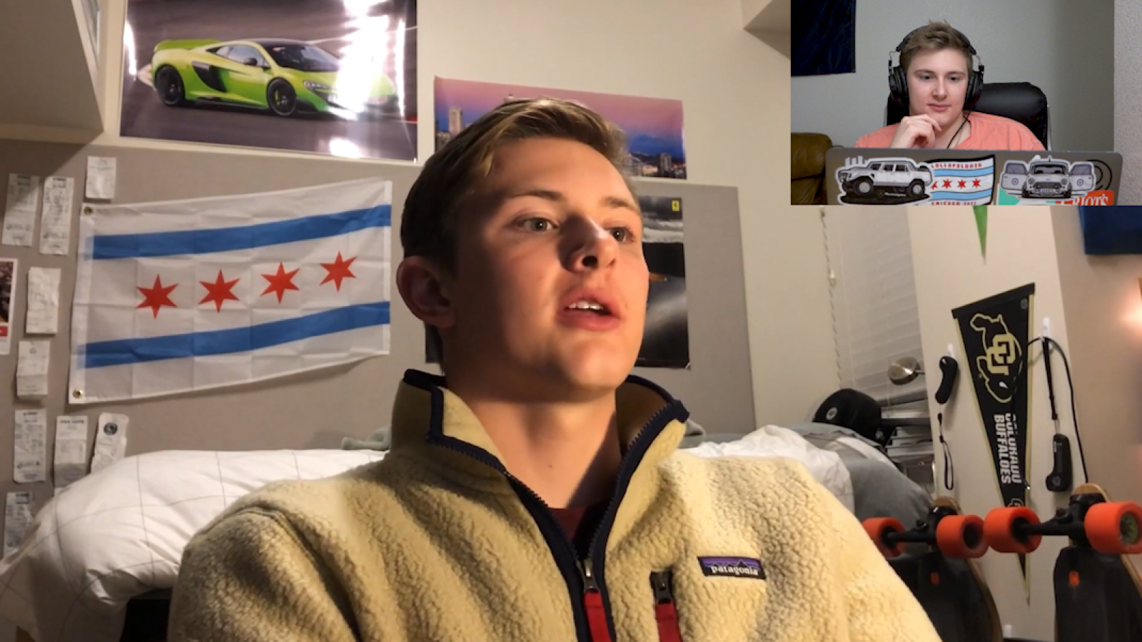 Austin reacts to his younger self in the top right corner of the frame. His younger self is seated, wearing a fuzzy jacket in his dorm room.