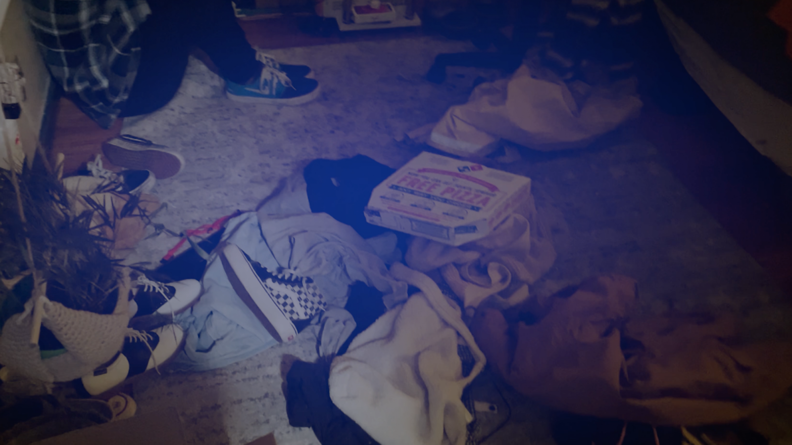 Bedroom floor with dirty clothes and pizza boxes