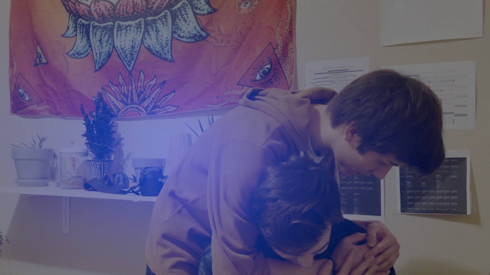 Two people in a headlock in front of a decorative wall