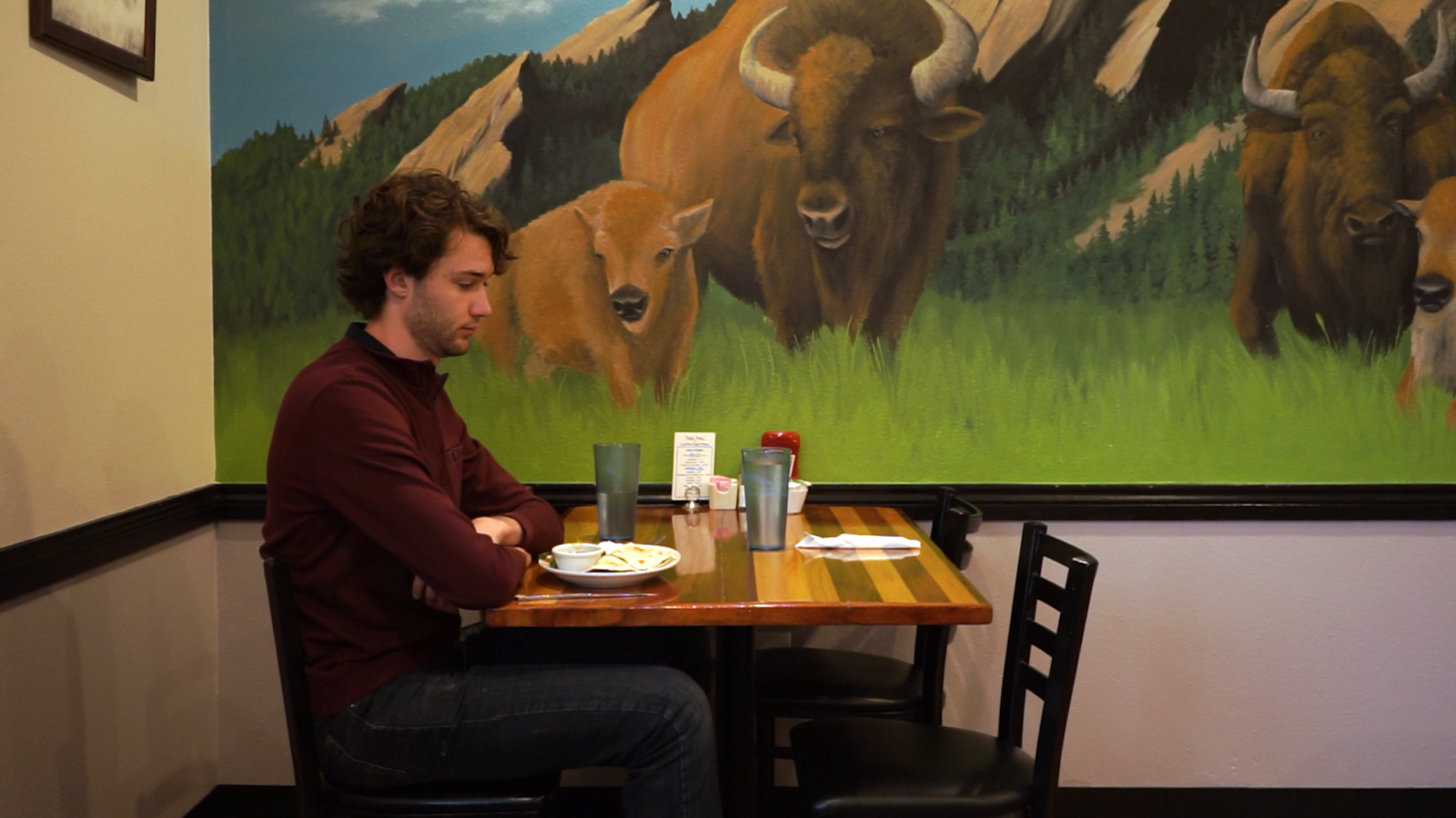 A man sits alone at a restaurant table. He appears dejected, as his date has yet to arrive.