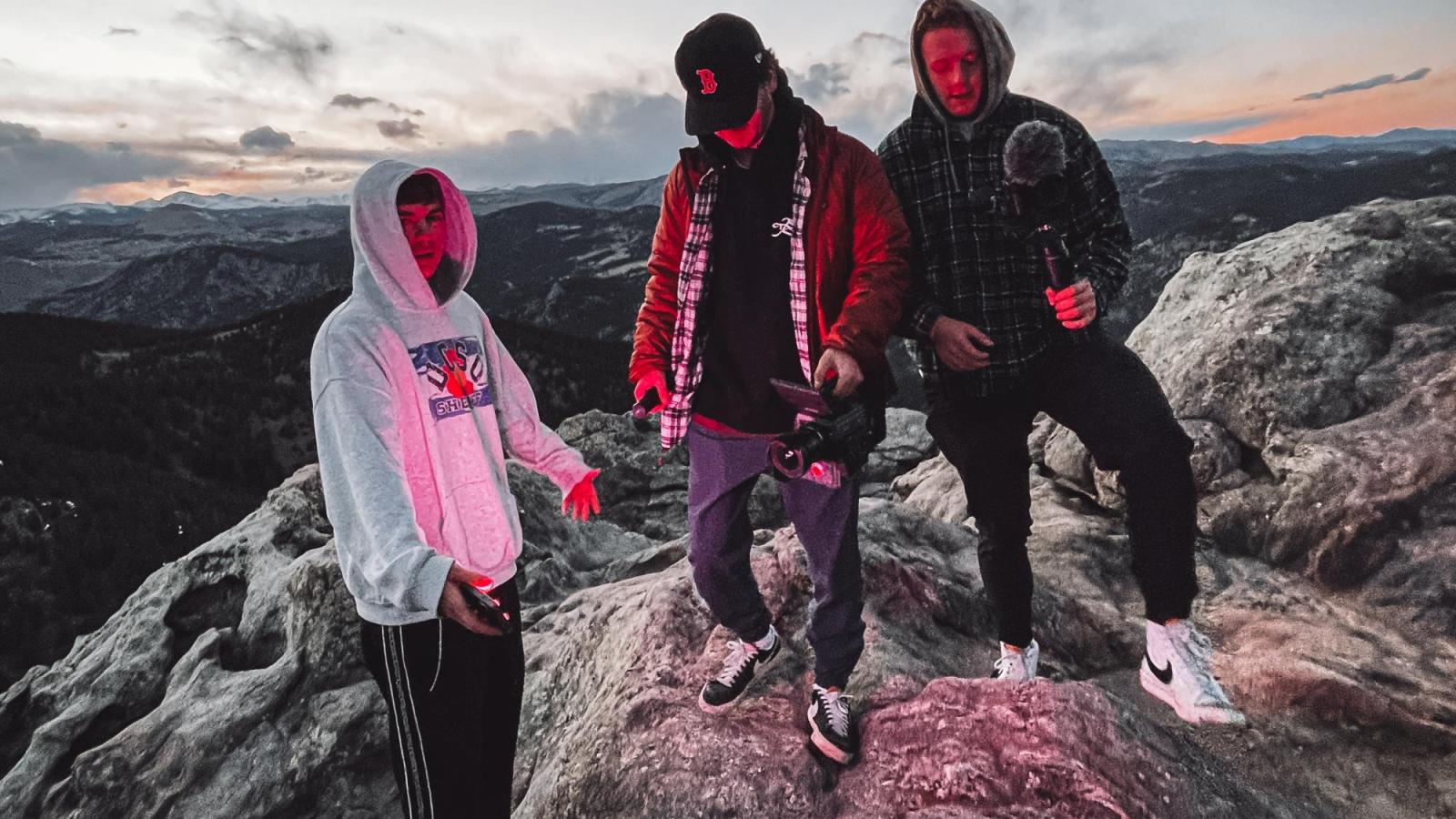 three people on top of mountain with cameras