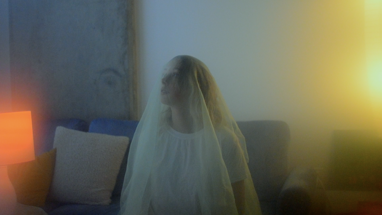 A diffused shot of subject wearing a veil and sitting on a sofa