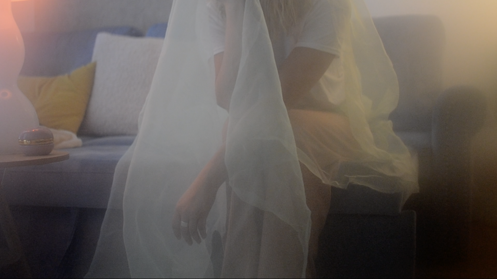A diffused shot of subject wearing a veil and sitting on a sofa