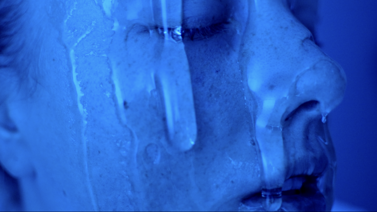 Subject in neon blue light with clear gel dripping down her face
