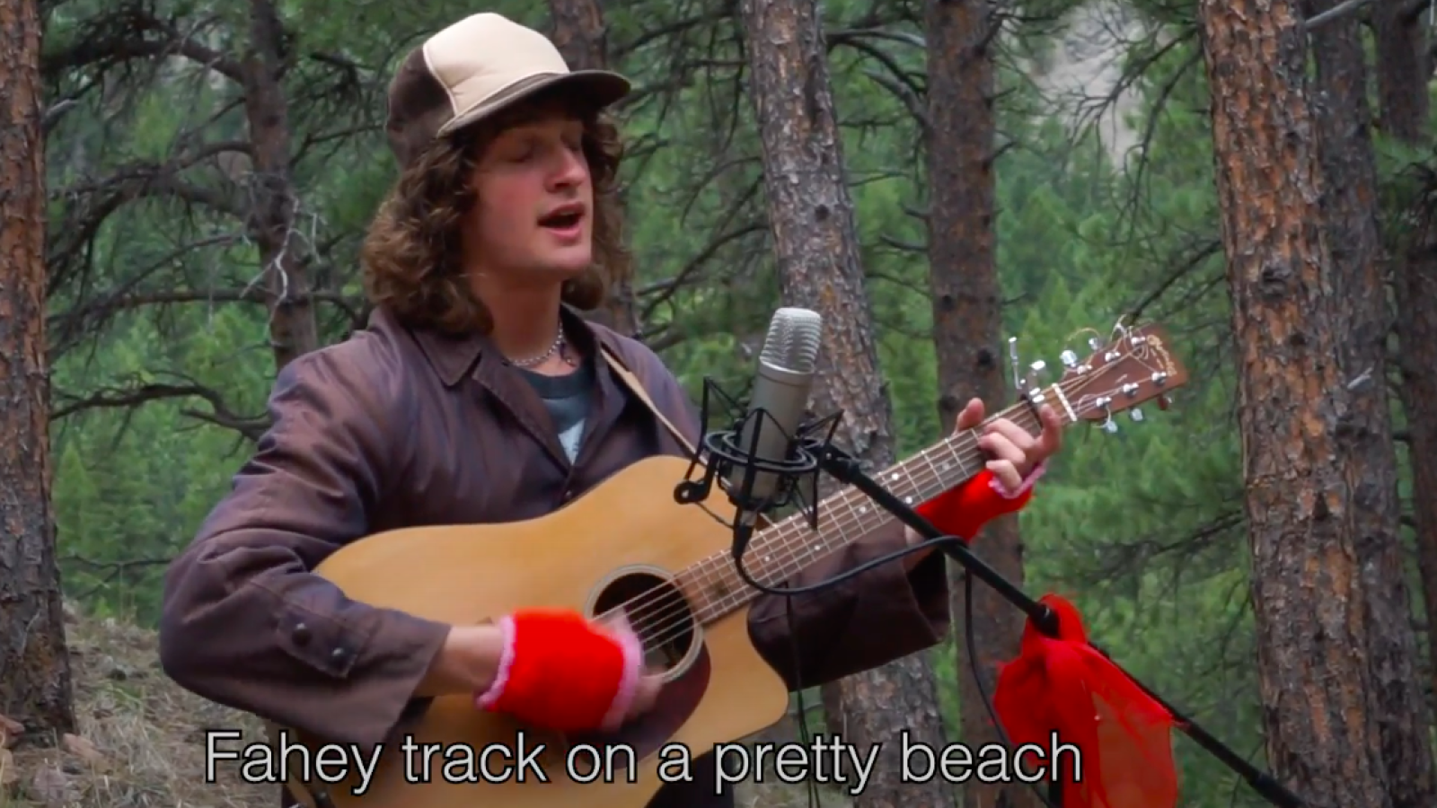 Person in the forest playing acoustic guitar and singing to a microphone