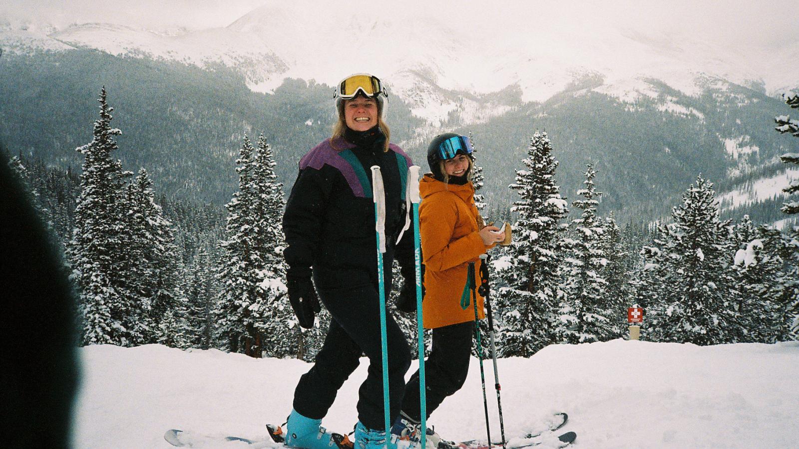 Two people holding their skis on top of a mountain