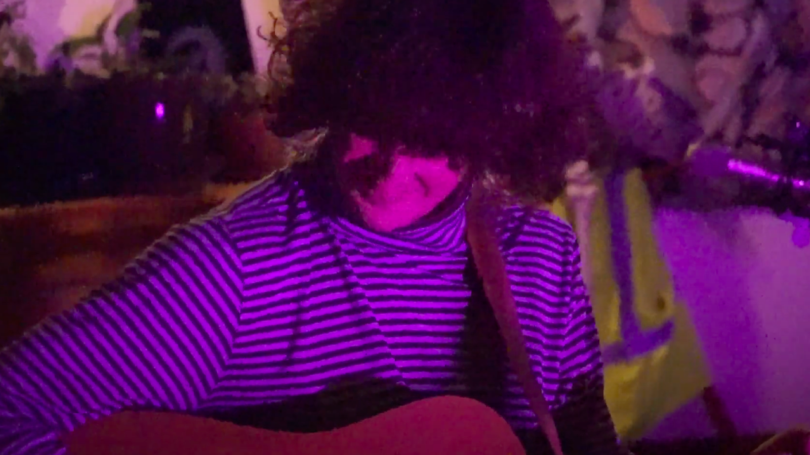 Person holding acoustic guitar indoors