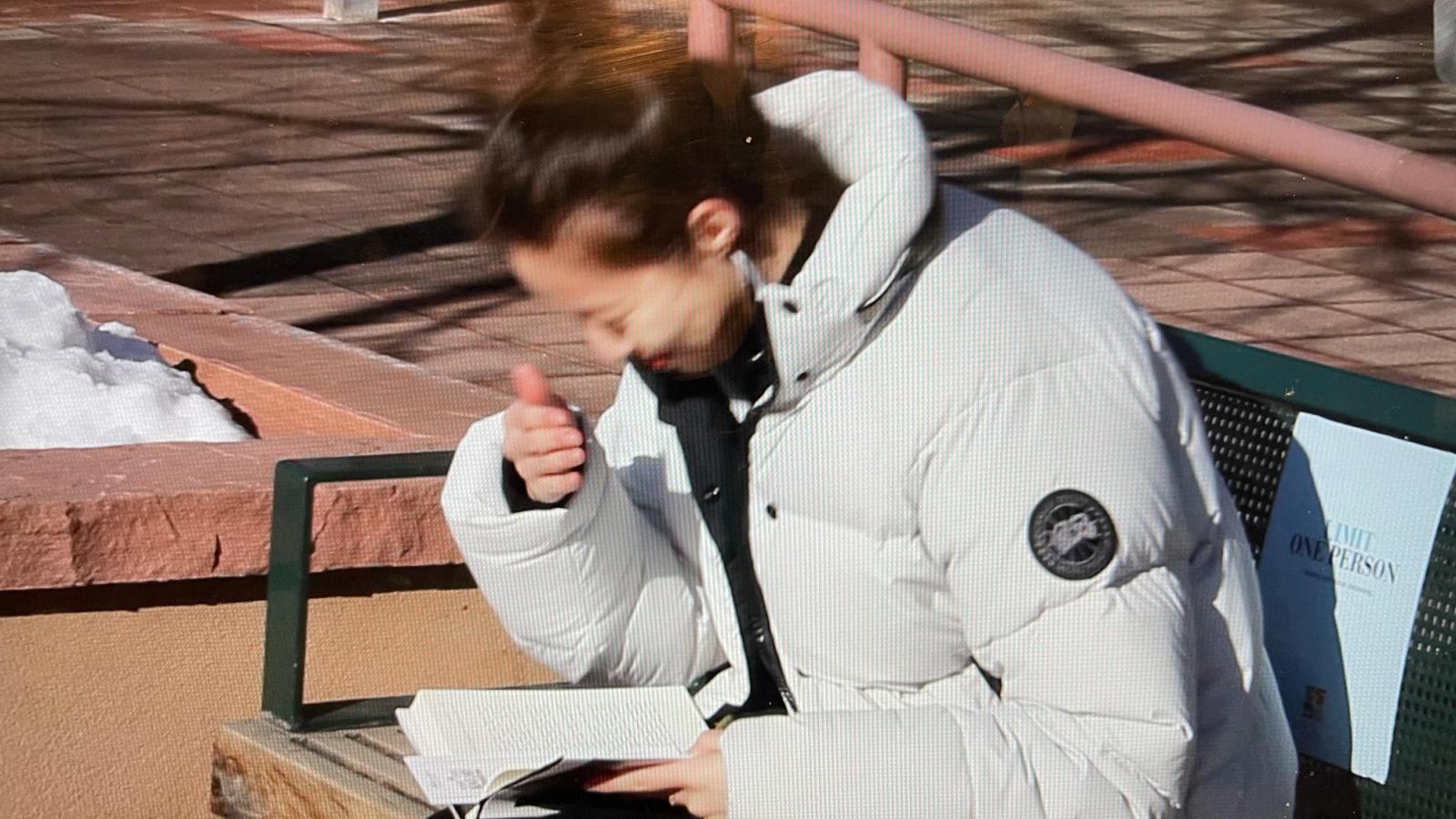 Person in a white coat reading a book and hiding from the sun