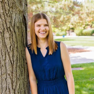 Woman standing by a tree smiling