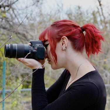 woman with red hair holding a DSLR