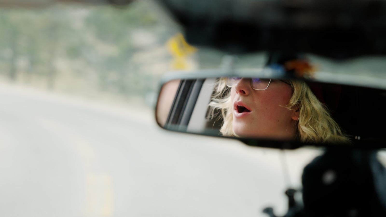 Reflection of woman in car rearview mirror