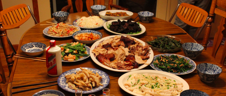 A Chinese feast with a variety of dishes spread on a round wooden table, ready for a communal meal.