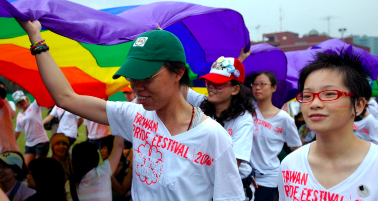 Participants in a pride march holding a rainbow flag.