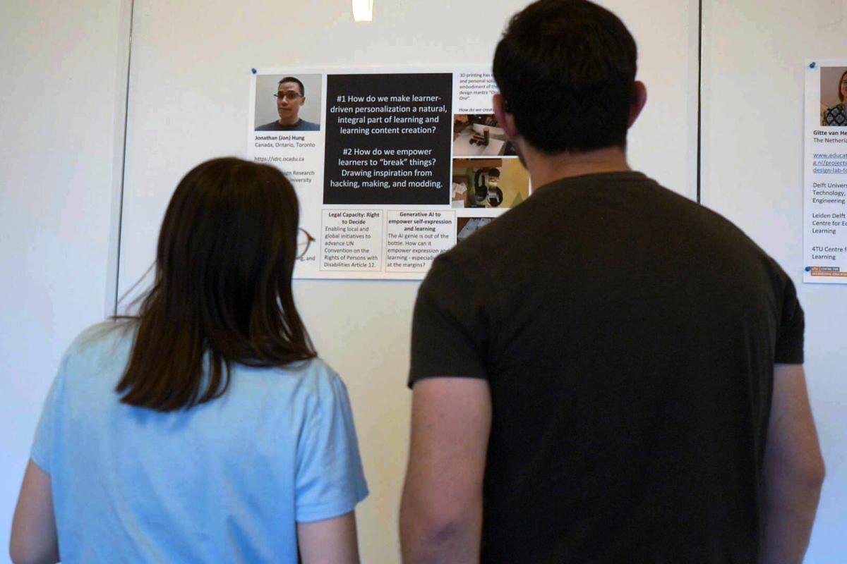 Over the shoulder view of two people looking at a poster on a white wall