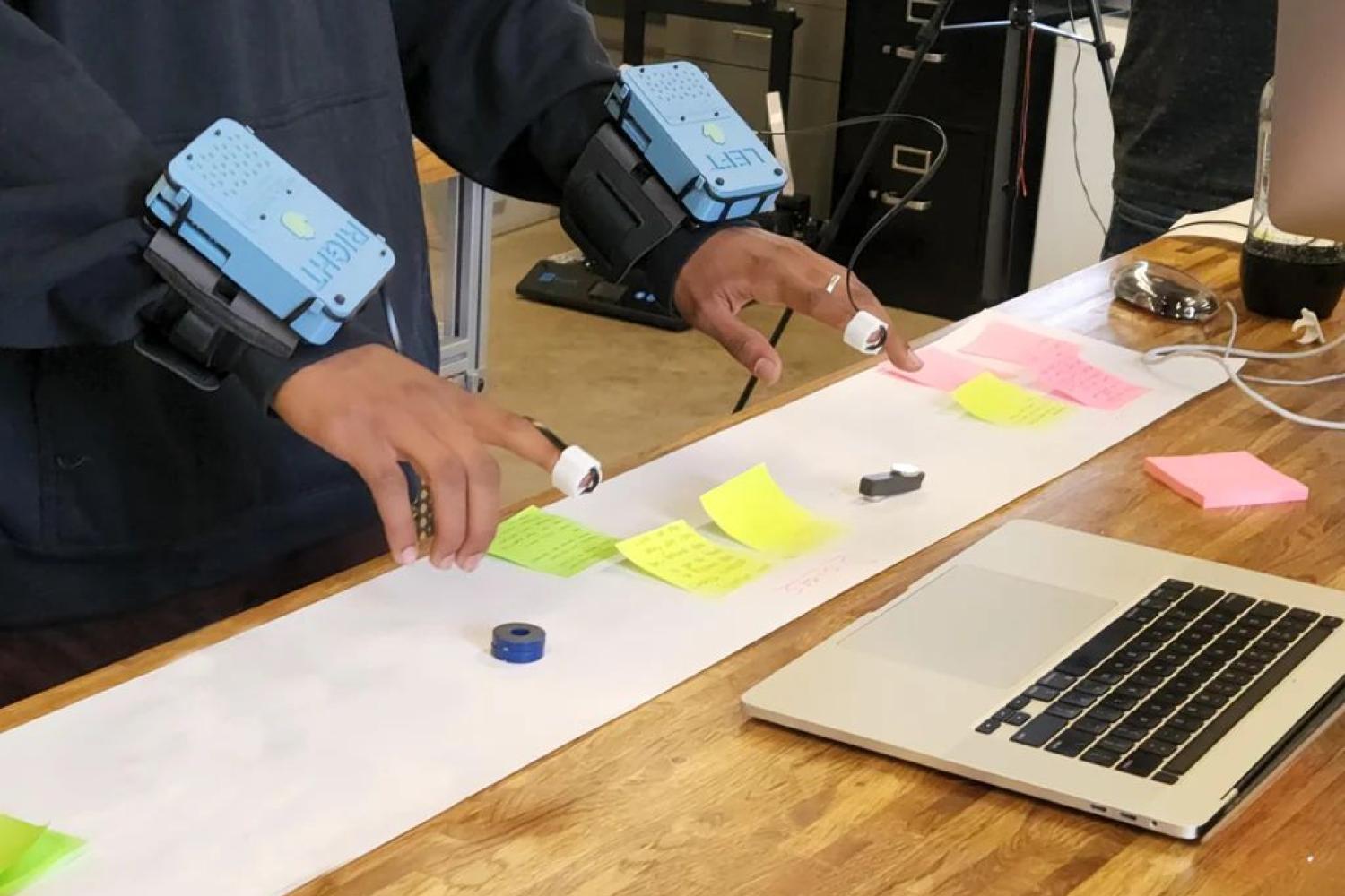Hands outstretched over laptop keyboard, sensory extension devices on wrists