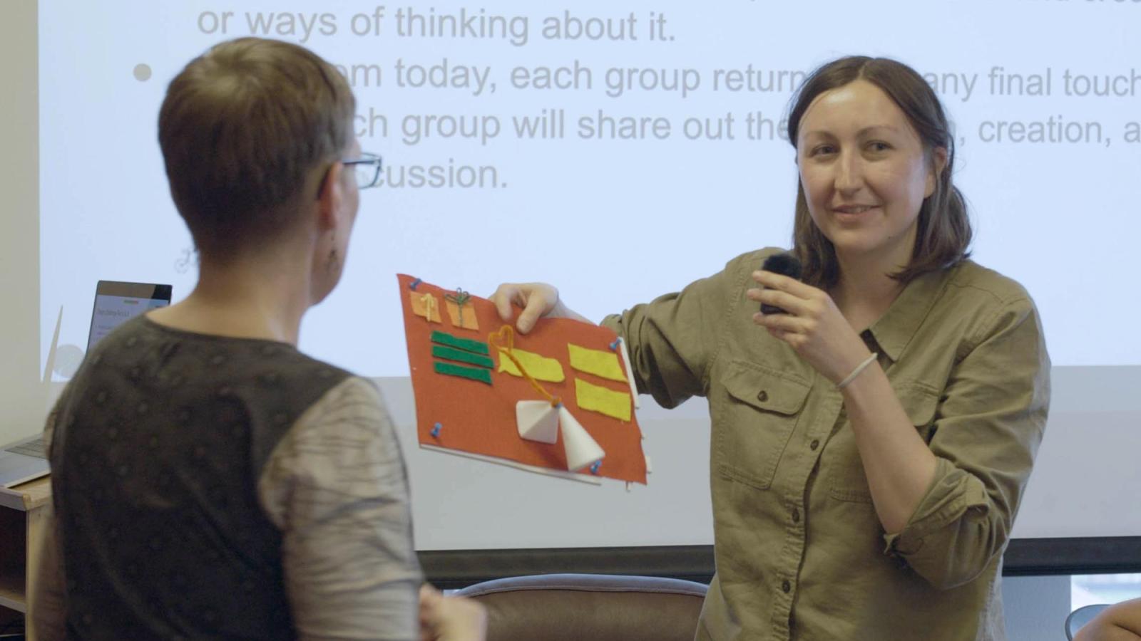 A woman holds up a construction paper design