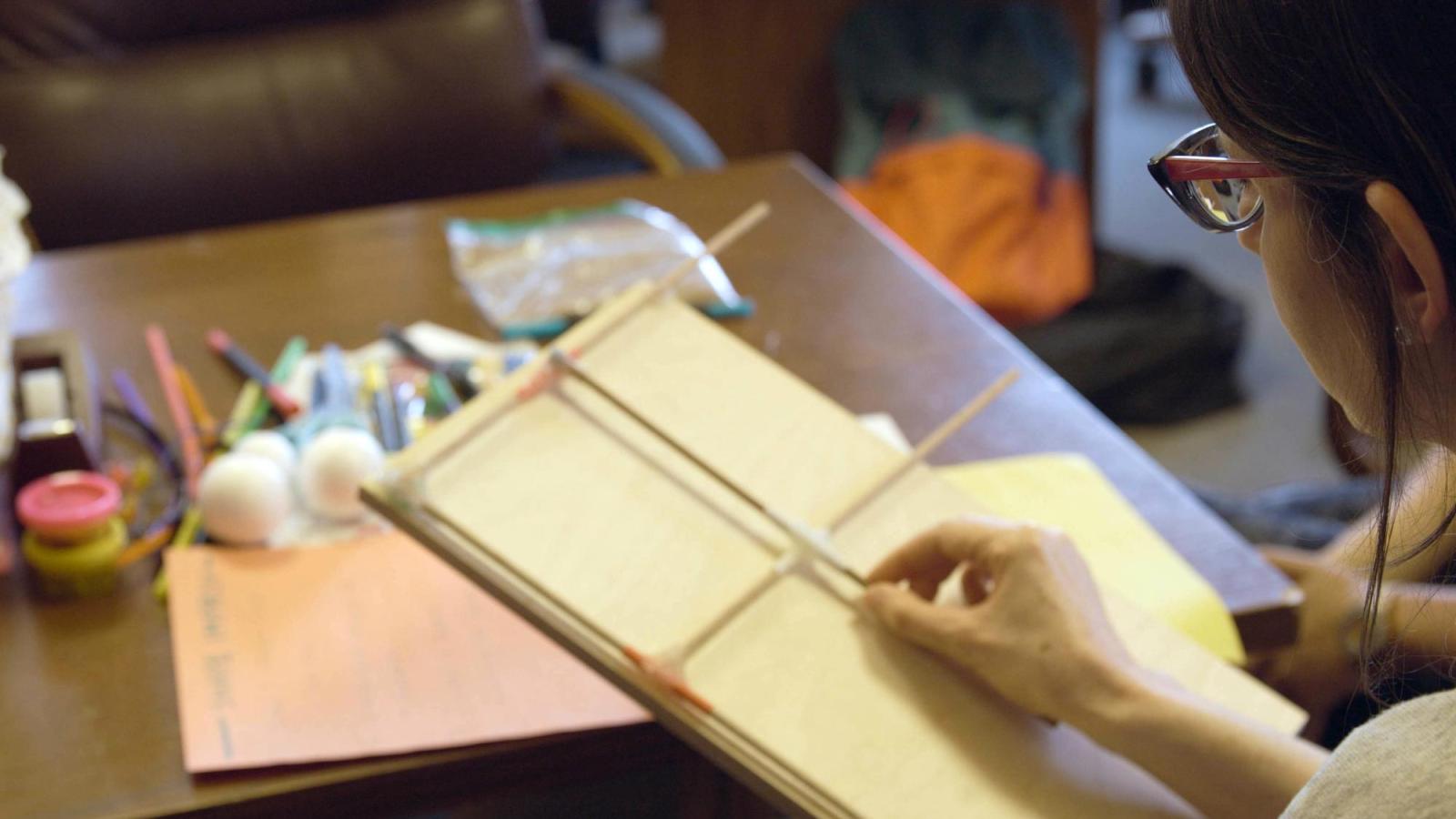 A woman studies a homemade device created in the design challenge