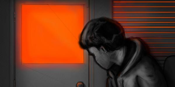 A teen boy in a room looks sadly at the door with a lighted window.
