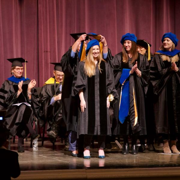 Sarah Grover is hooded by her co-mentor Professor Tiffany Ito (Bernadette Park, other co-mentor)