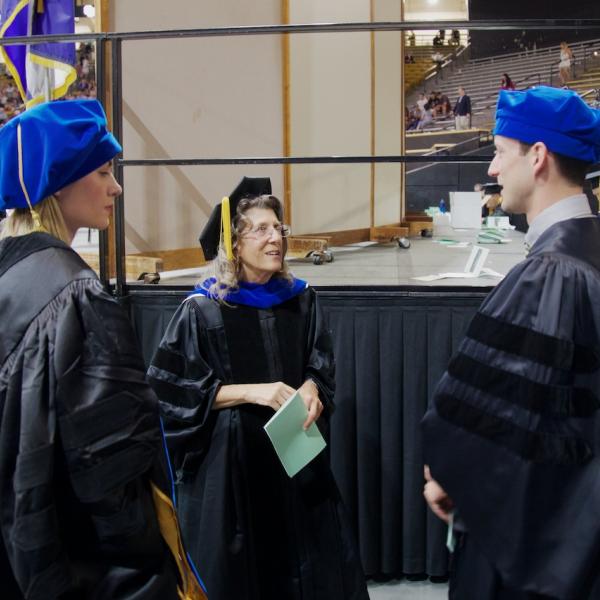 Prof. Linda Watkins chats with doctoral students Rachel Daut and Sam Dolzani before the ceremony